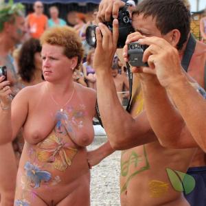 a crowd of nudists getting painted out and about
