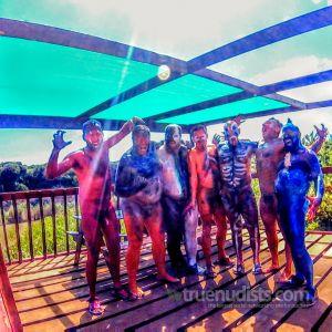 a crowd of men covered in bodypaint in the woods